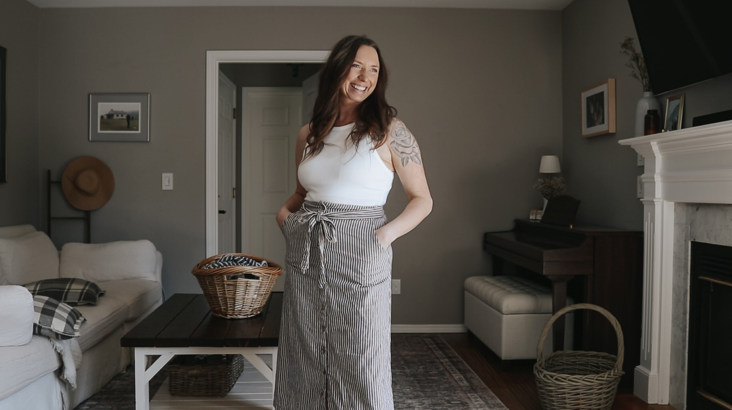 Christian homemaker stands in living room next to a laundry basket on a coffee table